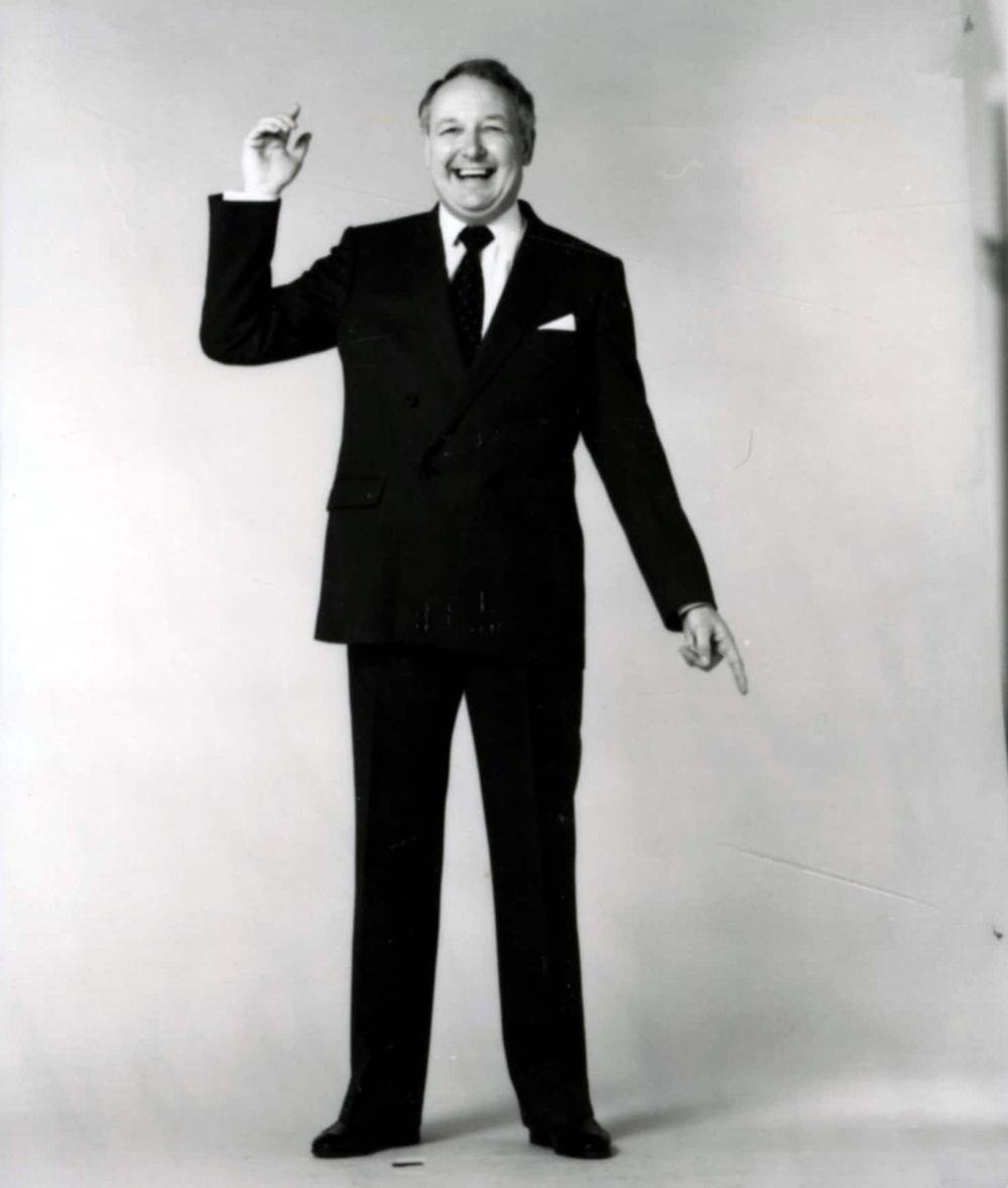Sir Freddie Laker in a studio portrait, holding a small model aircraft
